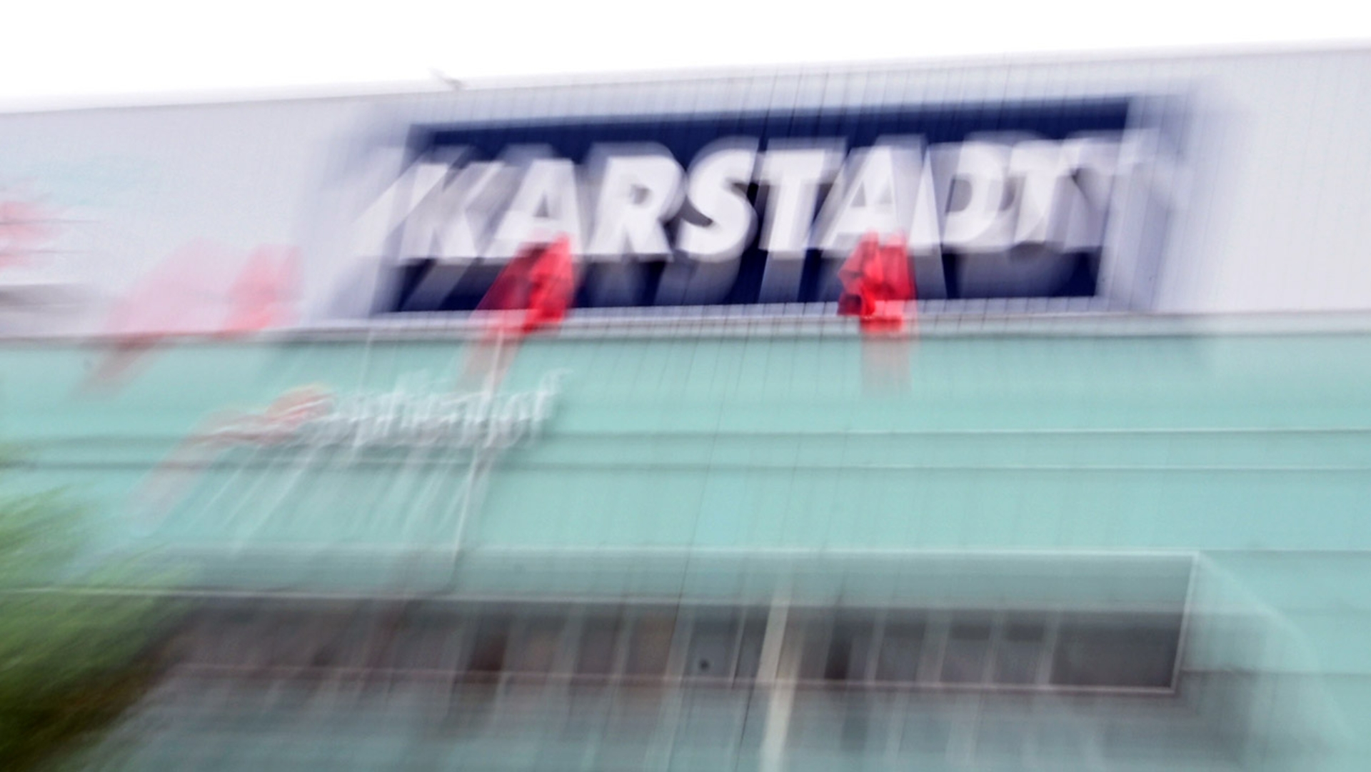  Verschwommen ist der Schriftzug Karstadt auf dem Dach einer Filiale zu sehen.