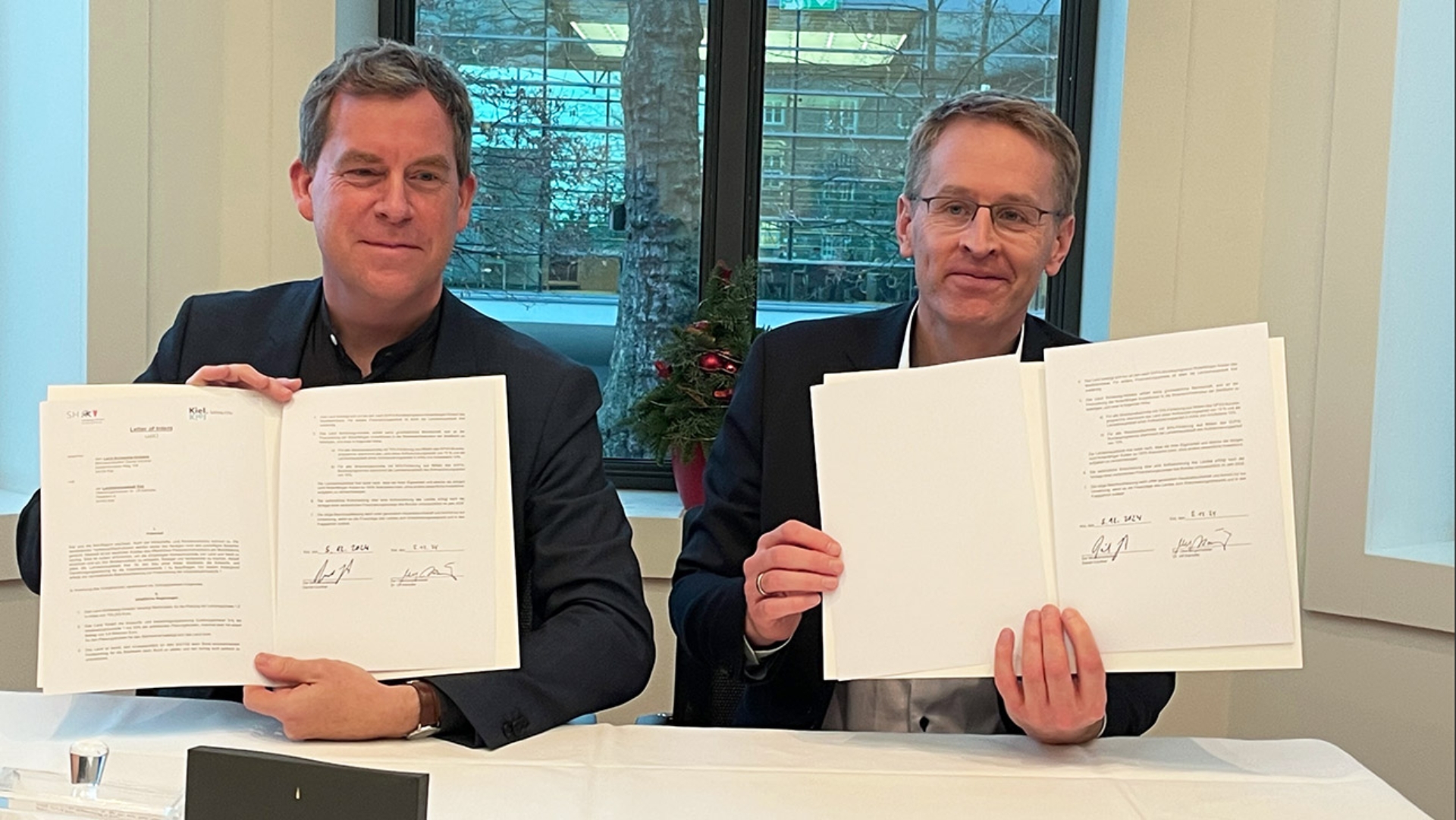 Ulf Kämpfer (SPD, l), Oberbürgermeister von Kiel, und Daniel Günther (CDU), Ministerpräsident von Schleswig-Holstein, präsentieren die gemeinsam unterzeichnete Absichtserklärung für die Kieler Stadtbahn.