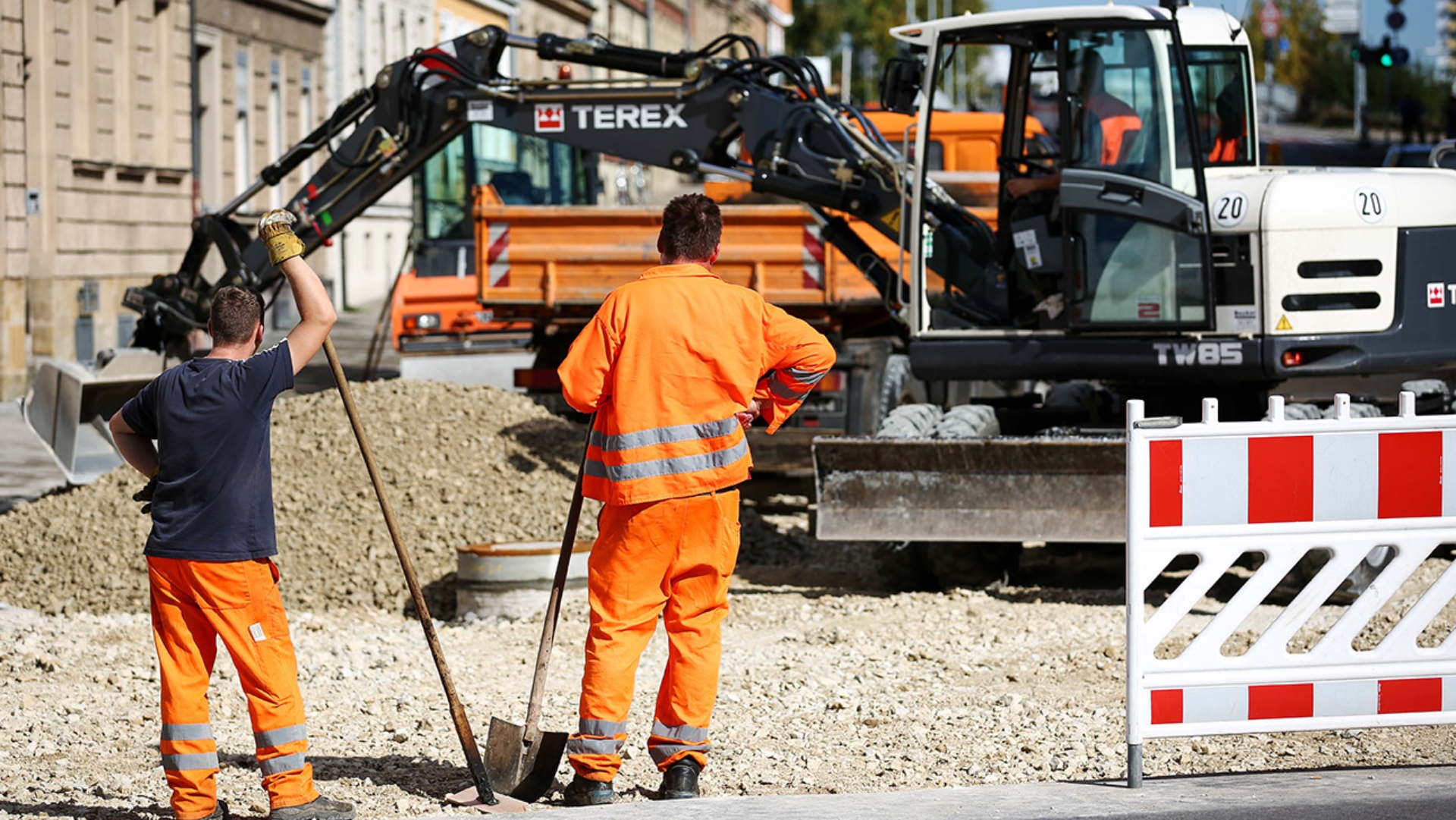 Ein Bagger reißt eine Straße in einer Wohnstraße auf.