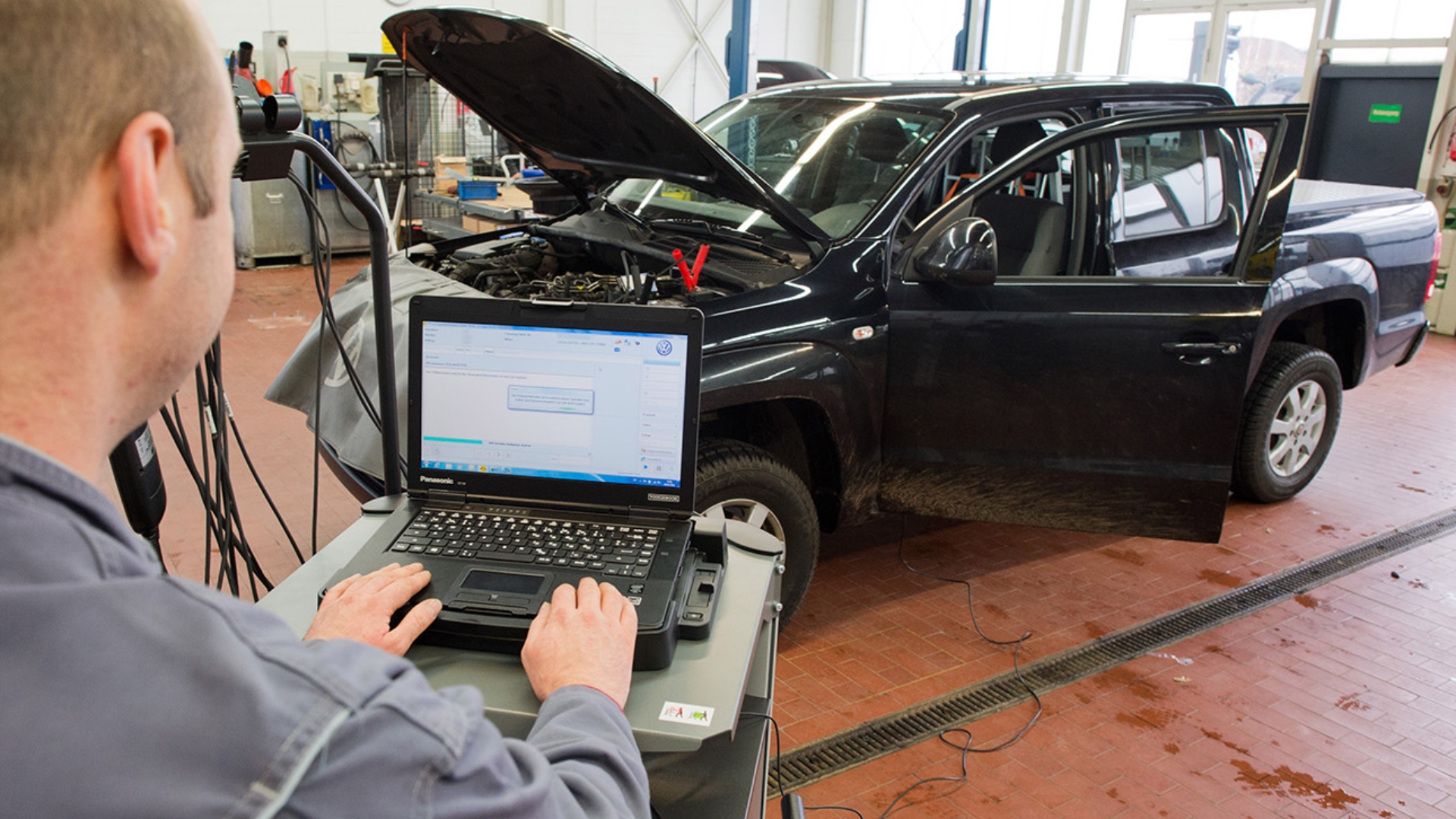 in Kfz-Meister lädt in einer Werkstatt im Rahmen der Rückrufaktion zum Abgasskandal ein Software-Update für das Steuergerät der Motorelektronik auf ein Auto.