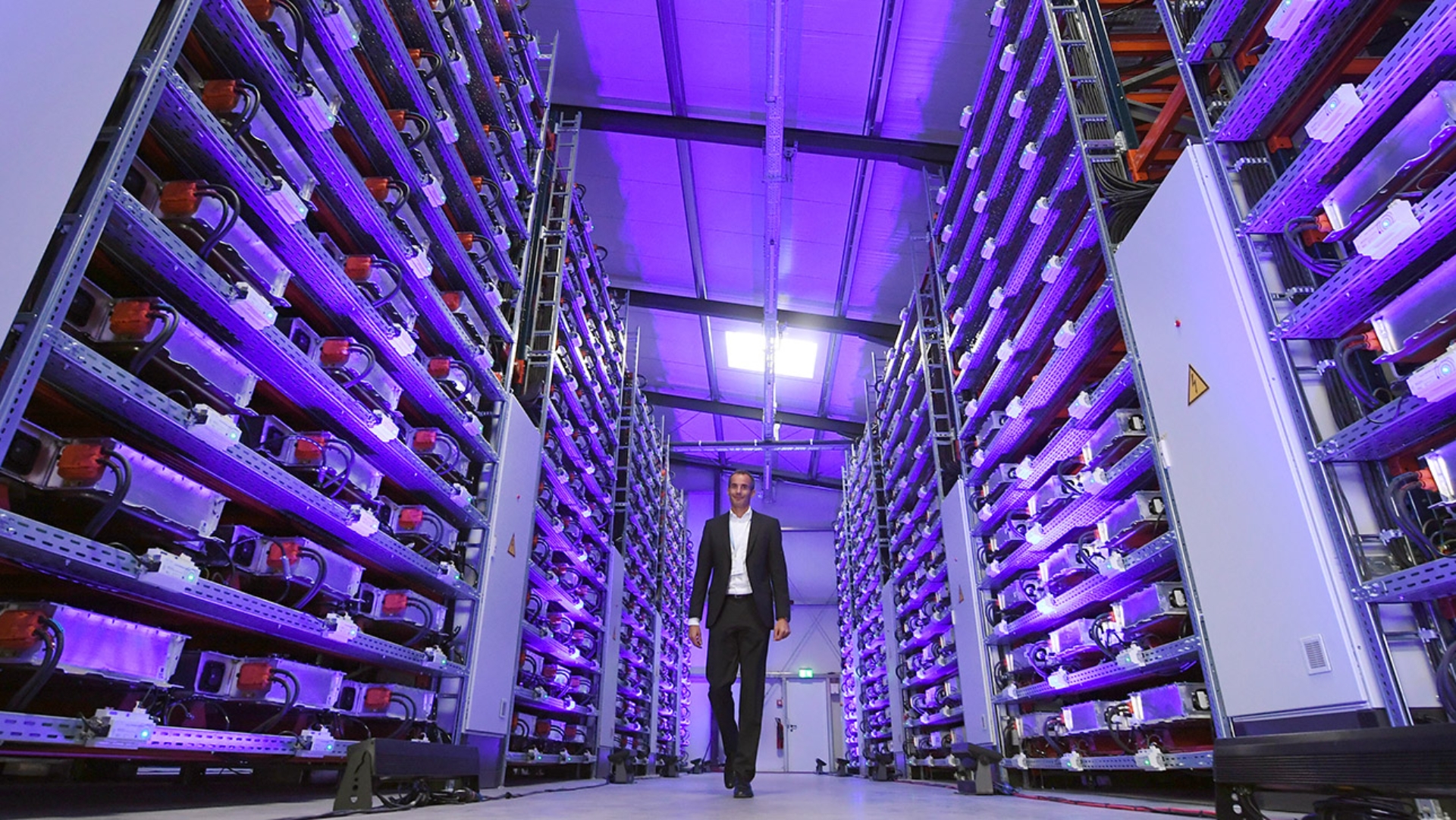 Ein Mitarbeiter geht in einem Gang der Speicherfarm eines großen Automobilproduzenten in München entlang. Die Speicherfarm verknüpft mit den Windrädern auf dem Werksgelände die dezentrale Eigenerzeugung aus erneuerbaren Energien mit einem lokalen Energiespeicher und einem industriellen Großverbraucher.