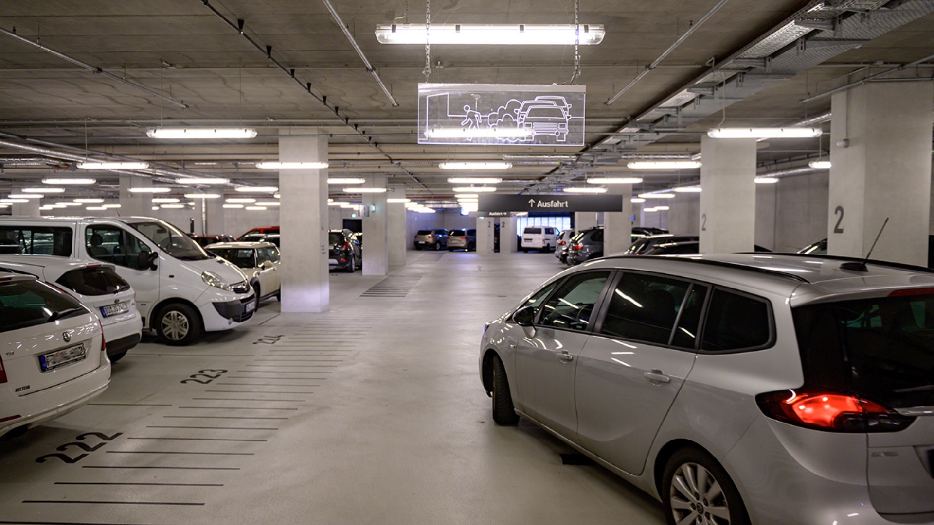 Ein Pkw fährt in ein Parkhaus, wo bereits viele Autos parken .