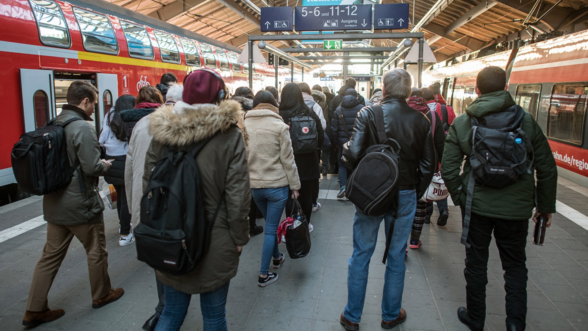 Eine Menschengruppe steht an einem Bahnsteig.