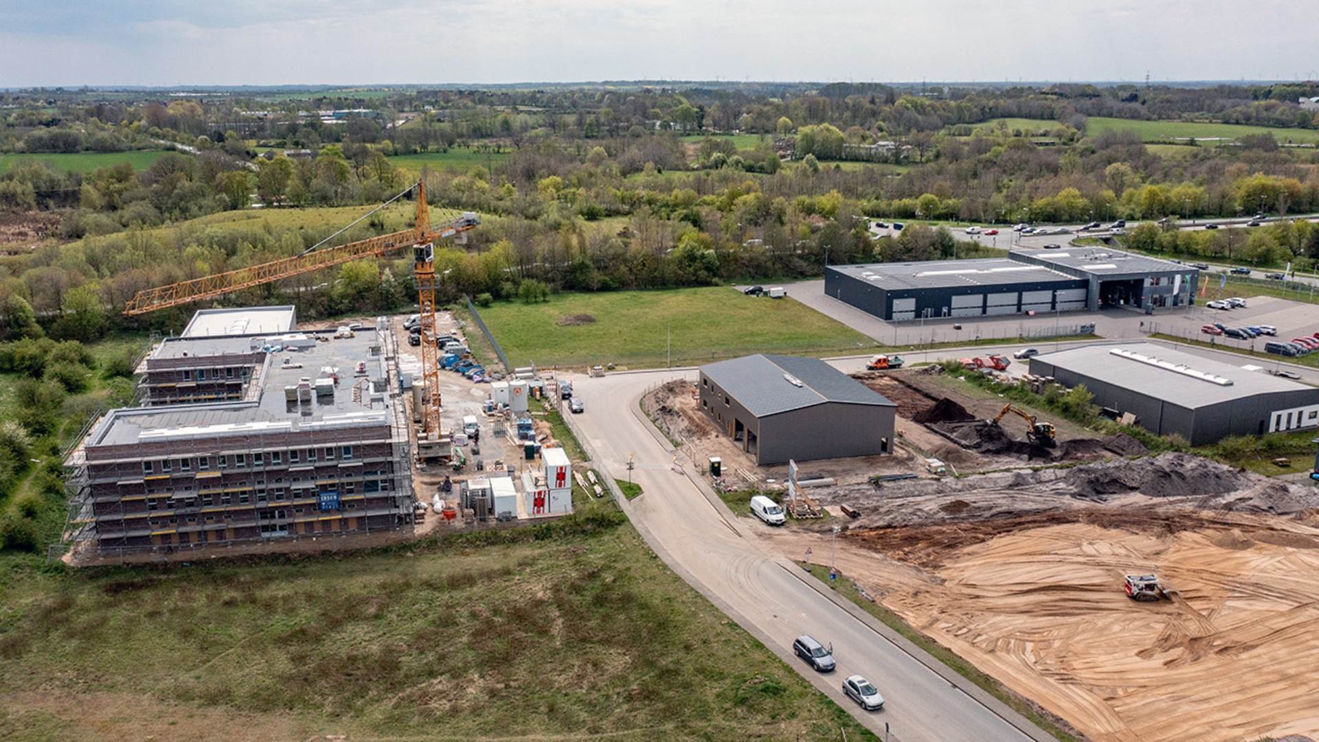 Ein Kran schwenkt über eine Baustelle in einem Gewerbegebiet im Süden von Flensburg. 