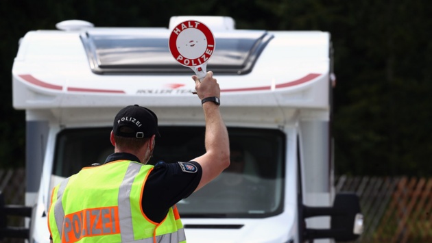 Ein Polizeibeamter stoppt mit einer Anhaltekelle ein Wohnmobil bei einer Kontrolle auf einem Parkplatz an der Autobahn 9.