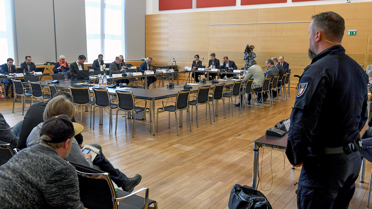 Blick in den Schleswig-Saal, wo Abgeordnete kurz vor Beginn einer Sitzung des Untersuchungsauschusses zur Rockeraffäre Platz genommen haben. Rechts auf dem Bild steht ein Polizeibeamter, links sitzen Zuhörer. 