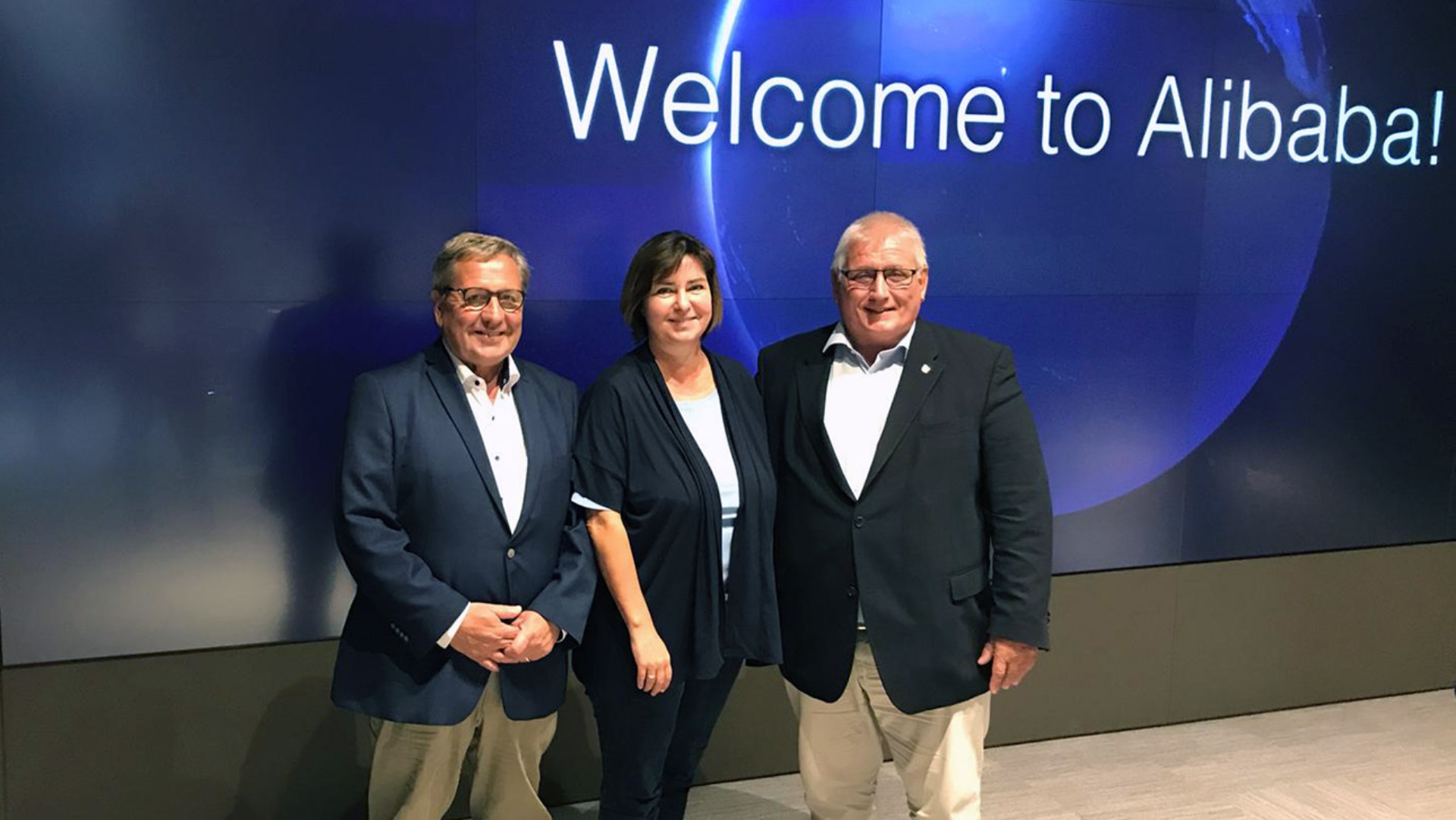 Die Landtagsabgeordneten Hans-Jörn Arp (CDU) und Birgit Herdejürgen (SPD) sowie Landtagspräsident Klaus Schlie vor einer digitalen Wand mit der Aufschrift „Welcome to Alibaba!“
