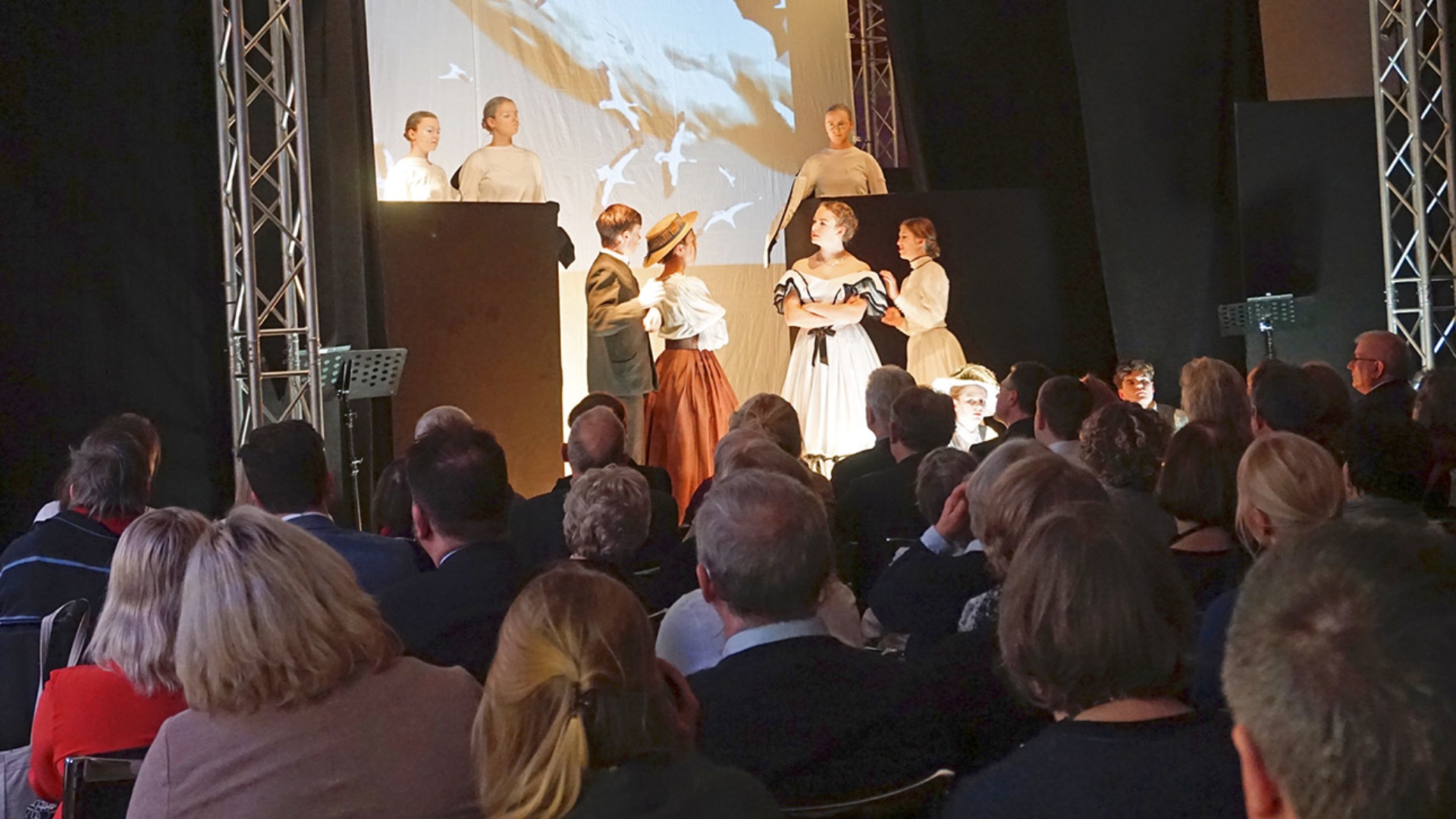 Jugendliche spielen das Theaterstück „Amphibien“ auf einer Bühne im Landeshaus. Sie sind in altertümlichen Kostümen zu sehen.