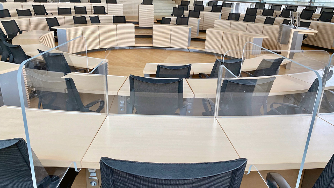 Schutzkonstruktionen aus durchsichtigem Acrylglas sind an den Sitzplätzen der Abgeordneten im Plenarsaal des Landtages montiert.