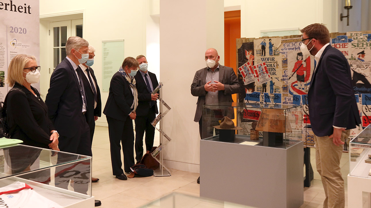 Die Museumsleiter Lars-Erik Bethge (2. v. r.) und Hauke Grella (r.) geben Einblicke in die Exponate ihrer gemeinsamen Ausstellung im Landeshaus.