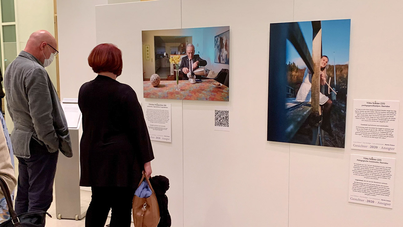 Besucher betrachten Porträts von Menschen, die für die Ausstellung fotografiert wurden.