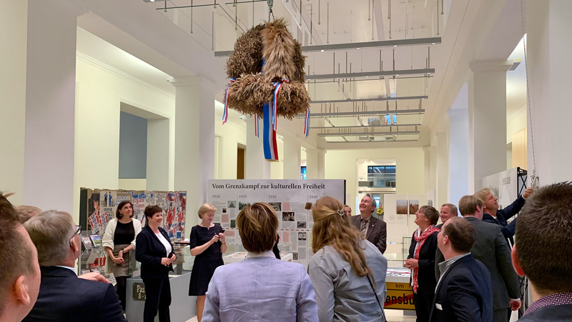 Gemeinsam mit Abgeordneten hängen Mitglieder der Landjugend die Erntekrone in der Eingangshalle auf.