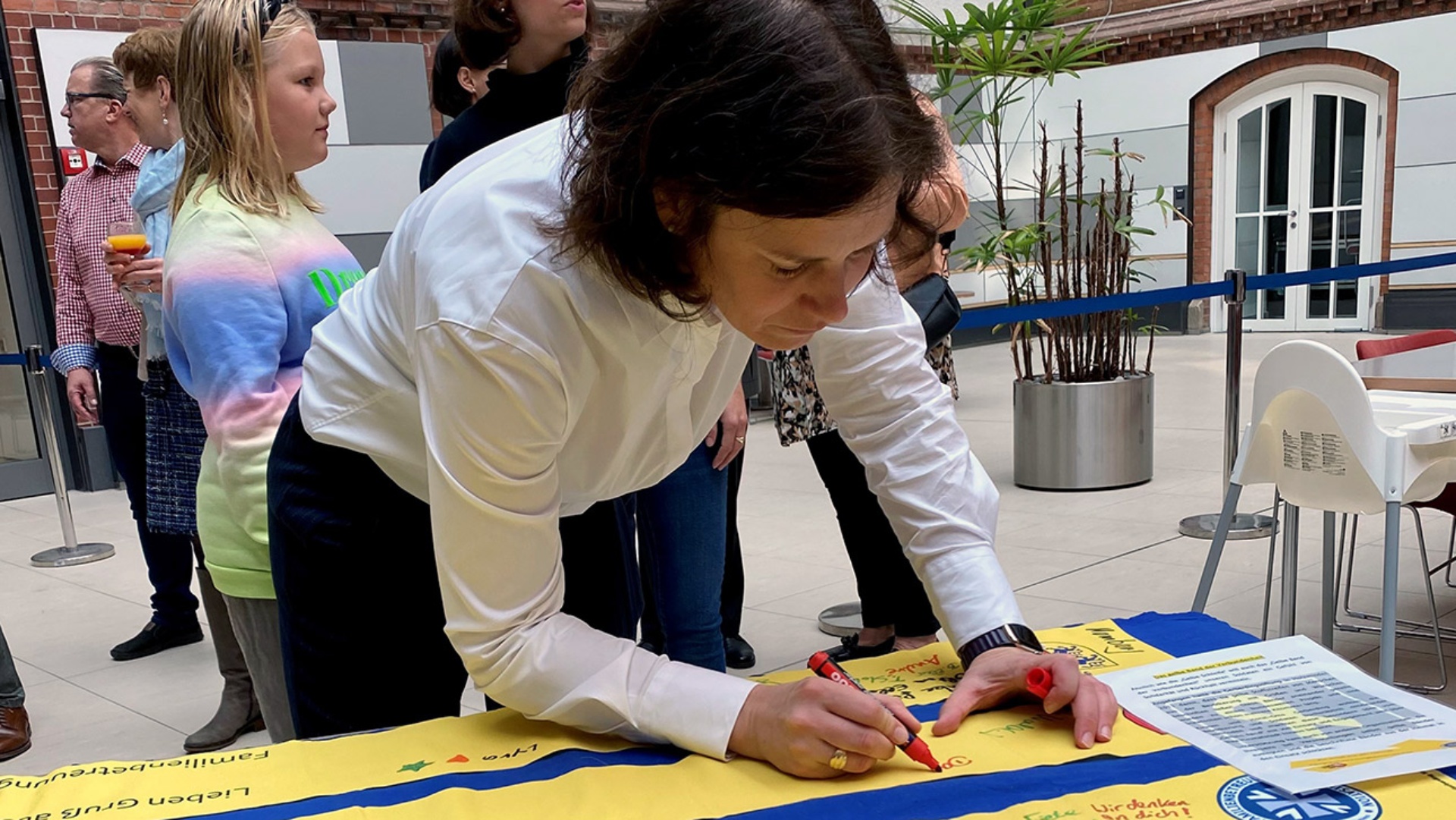 Landtagspräsidentin Kristina Herbst unterschreibt auf dem "Gelben Band der Verbundenheit".
