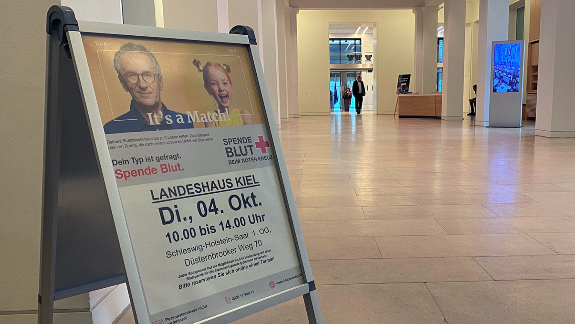 Plakat mit Blutspende-Termin steht in der Eingangshalle des Landeshauses.