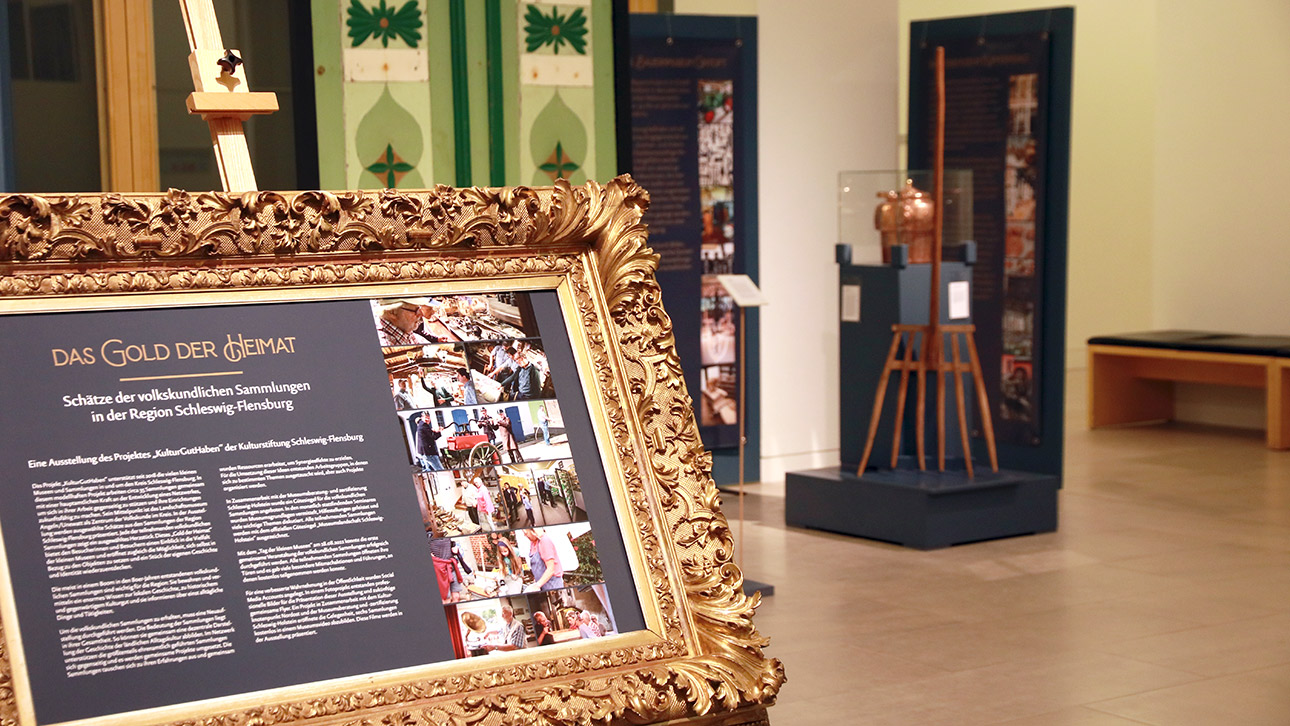Eine Tafel mit goldenem Rahmen weist auf die Ausstellung "Das Gold der Heimat" hin