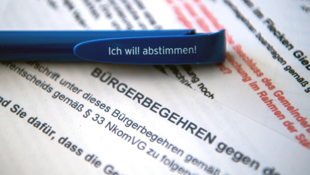 Ein Kugelschreiber mit dem Slogan "Ich will abstimmen" liegt auf einem Stapel Formulare zur Bürgeranhörung.