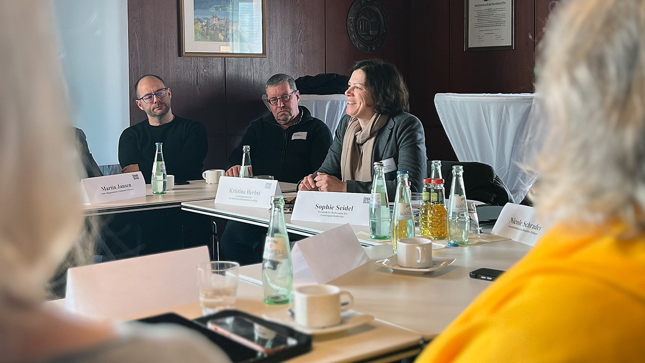 Parlamentspräsidentin Kristina Herbst sitzt an einem Tisch und unterhält sich mit Mitgliedern der Insel- und Halligkonferenz.