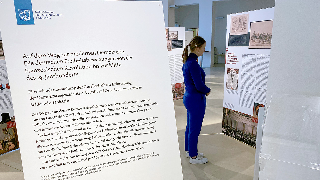 Eine junge Frau betrachtet die Stellwände der Ausstellung in der ersten Etage des Landeshauses.