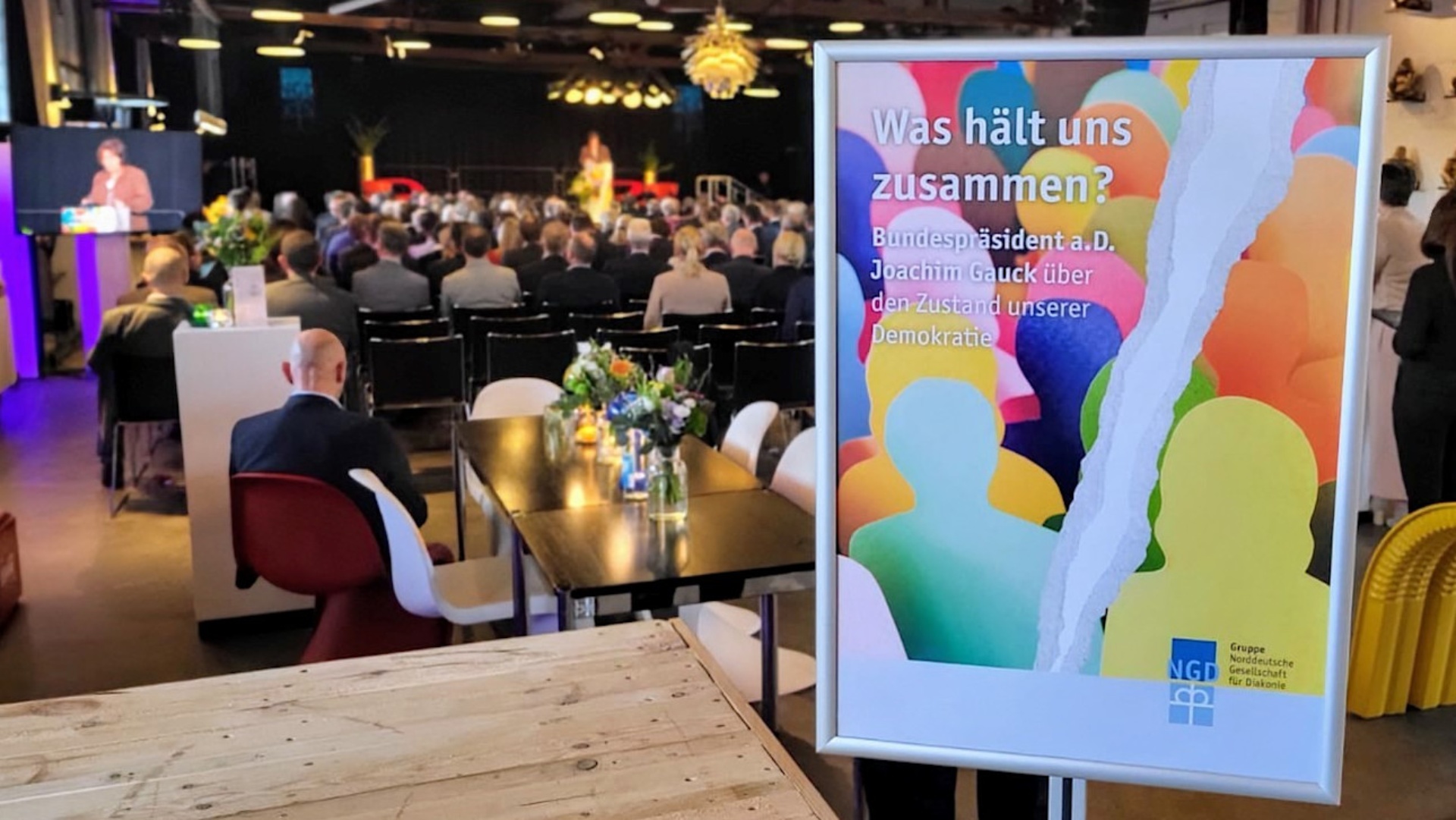 Ein Plakat zum Empfang der Gruppe Norddeutsche Gesellschaft für Diakonie (NGD) steht in einem Saal mit geladenen Gästen