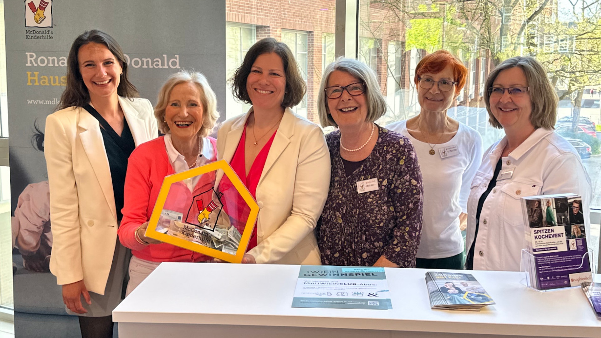 Gruppenbild zum Spitzenkochevent: Die Präsidentin des Freundeskreises Ronald McDonald Haus Kiel, Angelika Volquartz (rechts) und Landtagspräsidentin Kristina Herbst halten die Spendenbox