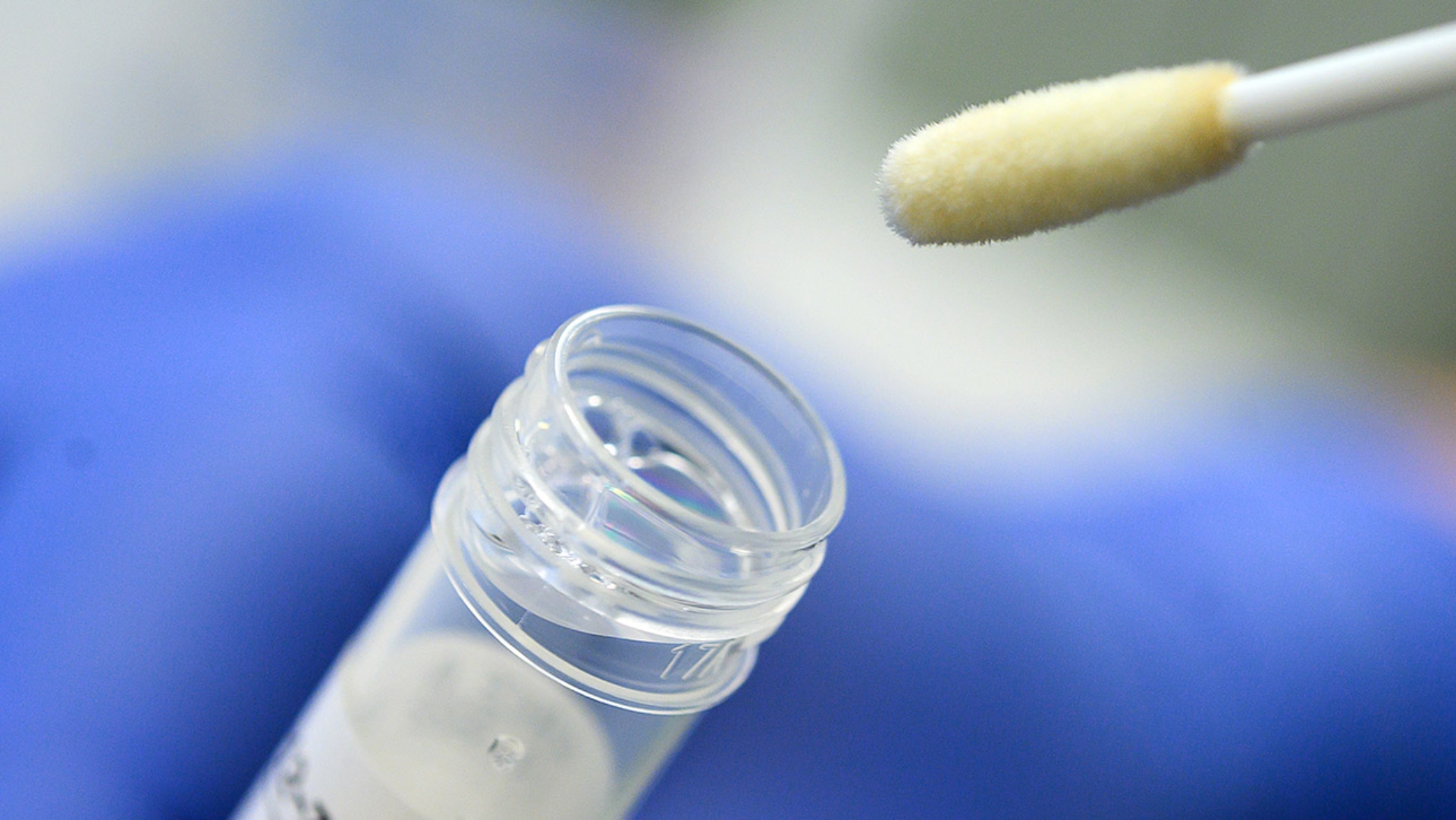 Ein Mann zeigt ein Stäbchen für einen Abstrich beim Corona-Test.