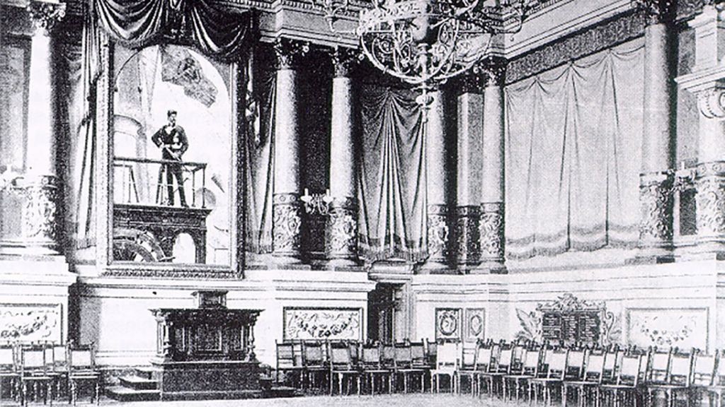 Die Aula der Marineakademie, der spätere erste Plenarsaal des Landtages. Das Gemälde an der Stirnseite zeigte Wilhelm II. von Preußen, der als Wegbereiter einer deutschen Marine auch entscheidend am Aufbau der Marineschule beteiligt war.