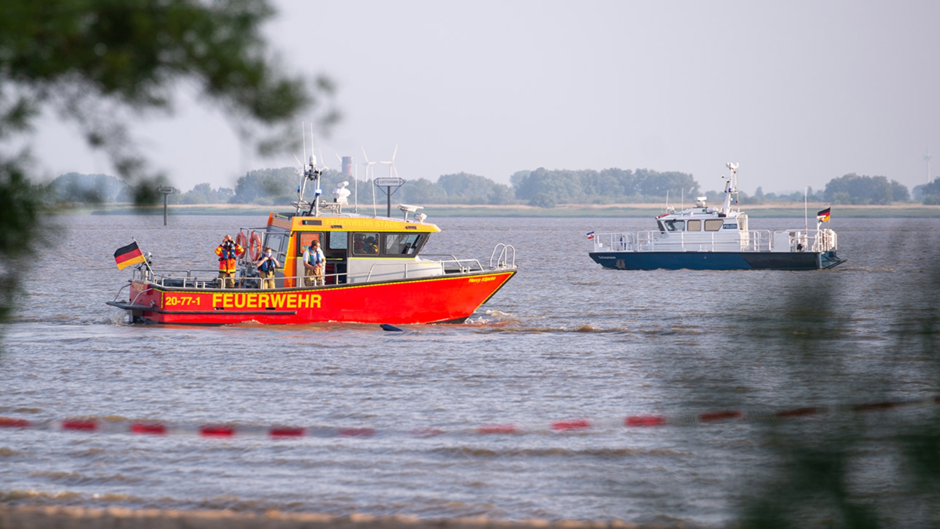 Ein Schiff der Feuerwehr und ein Polizei-Boot suchen nach einem Badeunglück auf der Elbe nach einer vermissten Person.