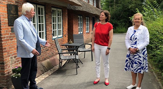 Gerd Vahder, Vorsitzender der Hans-Momsen-Gesellschaft, begrüßt Landtagspräsidentin Kristina Herbst (Mitte) und Ilse Johanna Christiansen vom Friesenrat vor dem Hans-Momsen-Haus.
